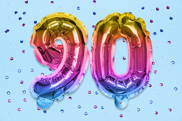 Rainbow foil balloon number, digit ninety on a blue background with sequins. Birthday greeting card...