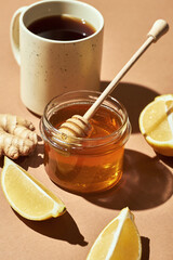 Minimalistic poster - composition with tea, lemon, honey and ginger on a brown background. Healing tea for colds.