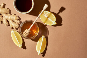 Minimalistic poster - composition with tea, lemon, honey and ginger on a brown background. Healing...