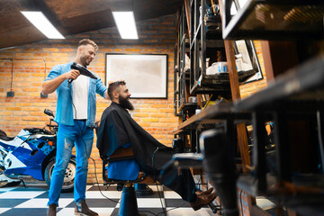 Fototapeta na wymiar Male hairstylist drying his customers hair
