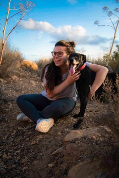 Joven sentada con su perro mientras hacen senderismo en una monta&ntilde;a. 