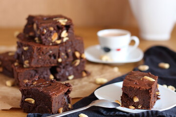 Break or snack time with a cup of coffee and chocolate brownies, served on wooden table.