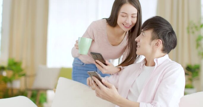 Happy young couple  looking at mobile phone in living room at home