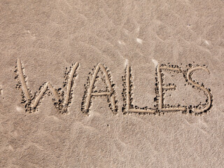 Wales texture writing background of handwritten text in sand on a Welsh seaside beach at a summer holiday travel destination resort, stock photo image