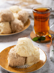 Eastern sweets - soft pashmak halva on a platter, in the form of round lumps, with a cup of Turkish tea.