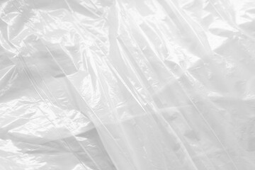 Reflecting light and shadow on creases and folds in white sheet of shiny fabric or plastic