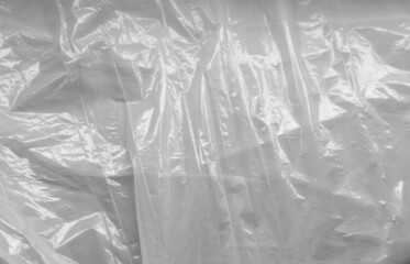 Reflecting light and shadow on creases and folds in scrunched white sheet of shiny fabric or plastic
