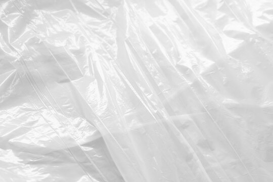Reflecting light and shadow on creases and folds in white sheet of shiny fabric or plastic