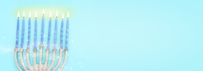 Image of jewish holiday Hanukkah with menorah (traditional candelabra) and candles over pastel blue background