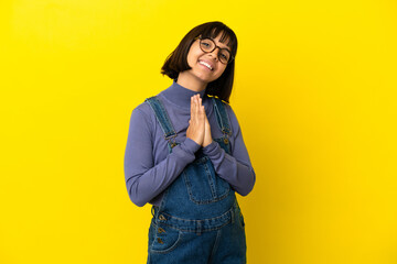 Fototapeta premium Young pregnant woman over isolated yellow background keeps palm together. Person asks for something