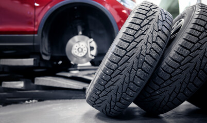 Selective focus winter tire with steel studs in service, in background car is lifted on lift