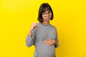 Young pregnant woman over isolated yellow background proud and self-satisfied