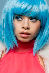 Portrait of asian woman in bright wig looking away isolated on blue