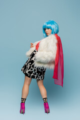 Pretty asian pop art woman in furry jacket and heels looking at camera on blue background