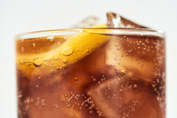 Cropped shot of sweet soda drink, glass of coke with ice cubes and lemon inside