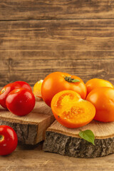 Assorted ripe tomatoes on a wooden stand. Fresh red and orange organic vegetables