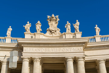 Fototapeta na wymiar A view of Vatican city coat of arms and saints statues on top of colonnades in Piazza San Pietro (St. Peter's Square)