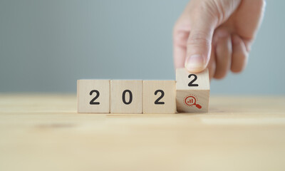 2022 forecast concept of  economy, business, sales, finance for business plan and development. Hand flips wooden cubes "2022" and "magnifying glass" symbol on beautiful background and copy space
