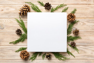 Flat lay Christmas composition. square Paper blank, pine tree branches, christmas decorations on Colored background. Top view, copy space for text