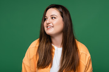 Fototapeta premium Positive woman with overweight looking away isolated on green