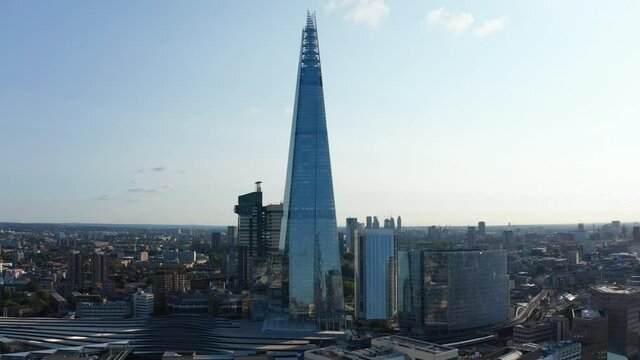 Slide and pan footage of tall Shard skyscraper with futuristic design. Tall modern office building next to London Bridge train station. London, UK