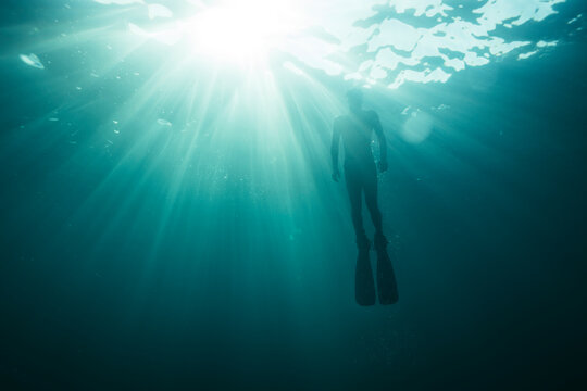 Underwater photo of freediver ascending to sea surface	