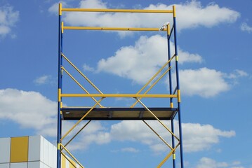 part of the metal structure of scaffolding from yellow blue tubes on the street against the...