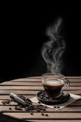 Hot steaming coffee in a glass cup and coffee bean on black background. Vertical format.