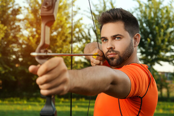 Man with bow and arrow practicing archery in park