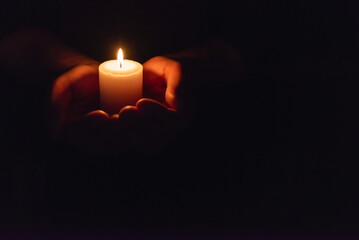 Hands holding burning candle in dark like a heart.Selective focus,black background.Copy space.
