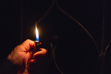 Woman hand holding a burning lighter in the dark black background.Closeup,selective focus.Copy space. - obrazy, fototapety, plakaty