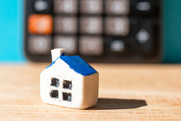 Obraz na płótnie Canvas Miniature house blurred calculator. Black blurred calculator.Real estate and mortgage concept.Selective focus,closeup.