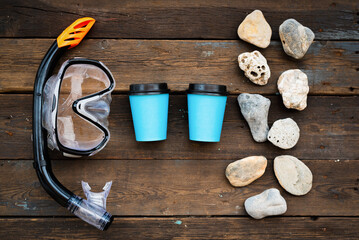 Coffee paper cups and sea pebbles stone on the wooden flat lay table background.