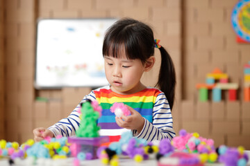 young girl playing creative building ball toy at home