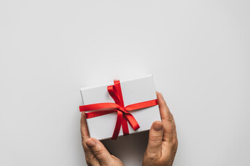 Weibliche Hände halten eine weiße Geschenk Box mit roter Schleife auf einem neutralen isolierten Hintergrund. Geburtstag.