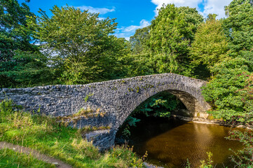 Fototapeta na wymiar A view across the old bridge at Stainforth Force, Yorkshire in summertime