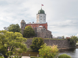 Medieval Vyborg Castle is Swedish-built fortress. White tower of Saint Olav with flag. Historical and architectural landmark.
