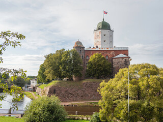 Fototapeta na wymiar Medieval Vyborg Castle is Swedish-built fortress. White tower of Saint Olav with flag. Historical and architectural landmark.