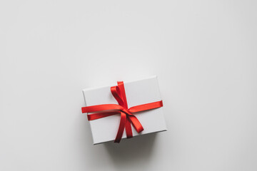 Eine weiße Geschenk Box mit roter Schleife auf einem neutralen Hintergrund. Draufsicht, Geburtstag.