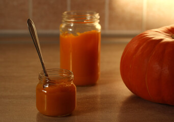 baby pumpkin puree in a glass jar with a spoon and fresh pumpkin