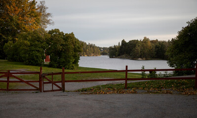 Red wooden hedge in front of a small beach by the lake