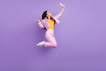 Fototapeta na wymiar Full length profile photo of nice young brunette lady do selfie jump wear jacket jeans sneakers isolated on violet background
