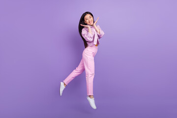 Full length profile photo of cute young brunette lady jump wear jacket jeans sneakers isolated on violet background