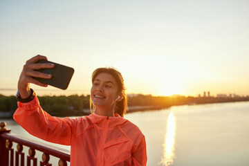 Overjoyed sporty woman train outdoors use smartphone