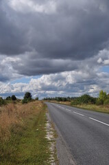 Fototapeta na wymiar Panorama along a deserted road. View of the road before the rain. Clouds in the sky.