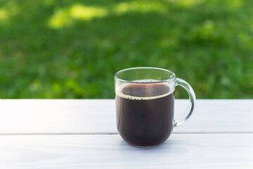 Cup of chicory drink on a wooden table against the background of nature.