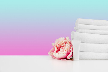 Stacked clean towels on white table against color background