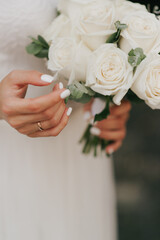 wedding bouquet and hand of the bride with white manicure close up