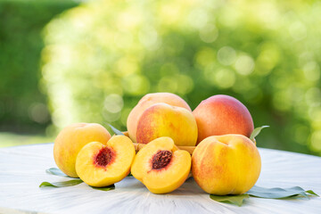 Yellow Peach with sliced on the wooden table over blurred greenery background, Fresh peach on wooden plate in wooden Background.