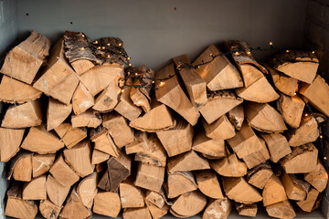 A stack of firewood. a big pile of firewood for the stove, background. fireplace with logs and lights on them.